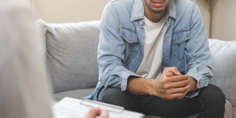 A visibly tense person seeking mental health support, sitting across from a psychiatrist during a counseling session.