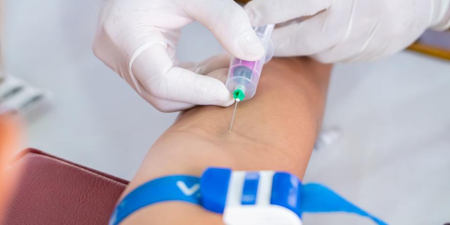 Medical professional in blue gloves conducting a venipuncture at Porunai Hospitals Tirunelveli for master health checkup packages for women
